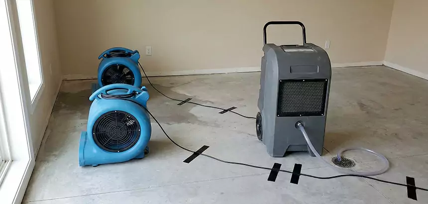 Air movers and a commercial dehumidifier set up for structural drying in a commercial room.
